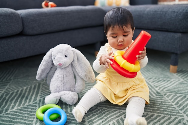 Adorable hispanic baby playing with hoops sitting on floor at home