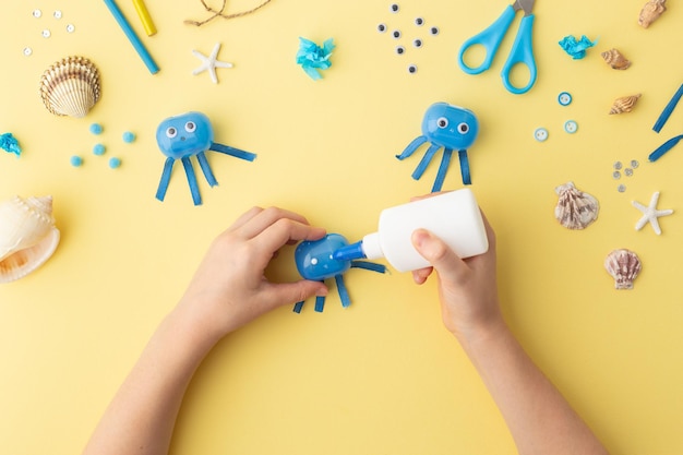 Photo adorable jellyfish made from plastic blue egg kids craft at home or kindergarten hands making diy