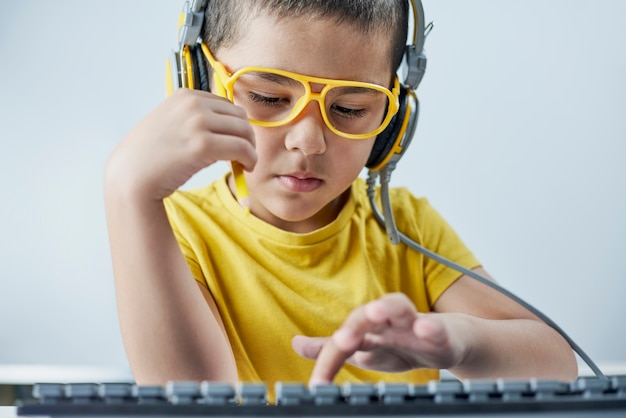 An adorable kid in a yellow t-shirt with a headphone listening online course.