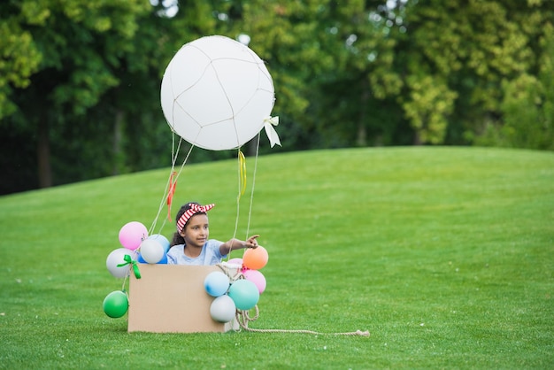 Adorable little african american girl playing with diy hot air balloon in park