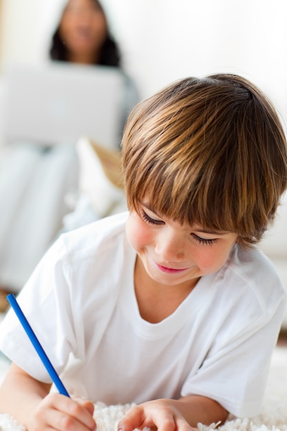 Adorable little boy drawing lying on the floor 