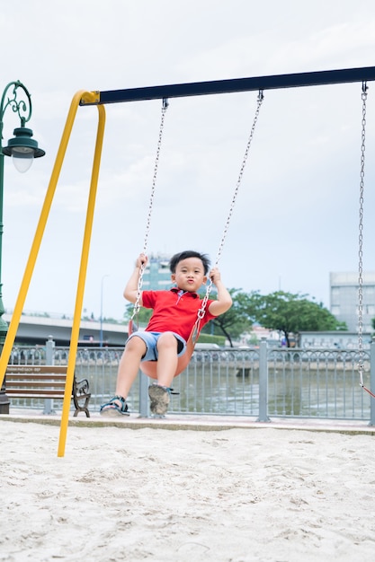 Adorable little boy having fun on a swing outdoor