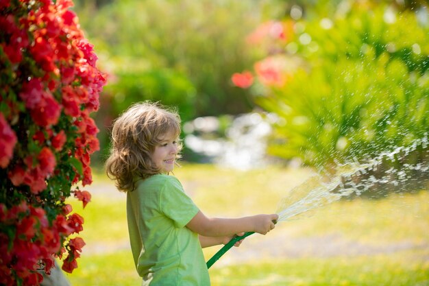 Adorable little boy is watering the plant outside the house concept of plant growing learning activity for kid and child education for the tree in nature