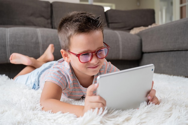 Adorable little boy using a digital tablet on the floor at home