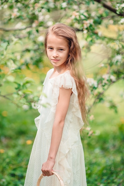 Adorable little girl in blooming apple garden on beautiful spring day