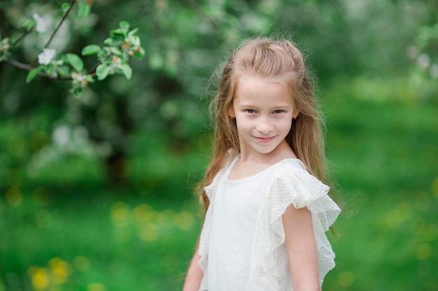 Adorable little girl in blooming apple garden on beautiful spring day