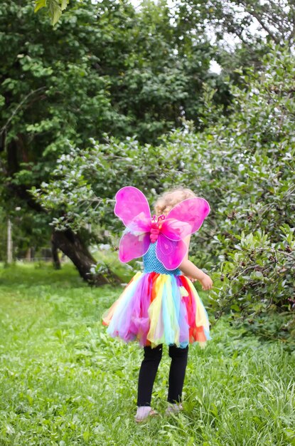 Photo adorable little girl in colorful rainbow dress playing in the park