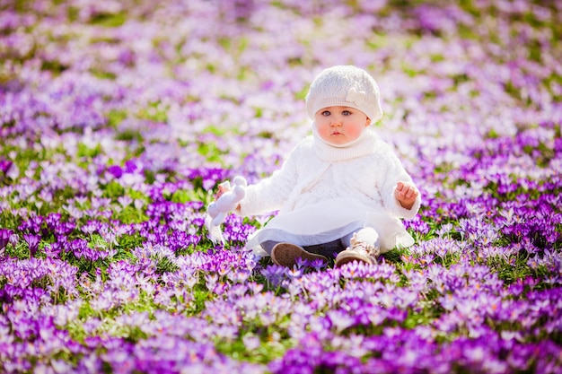 Adorable little girl enjoying spring and sun among the spring flowers crocuses