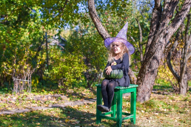 Adorable little girl in Halloween which costume having fun outdoors