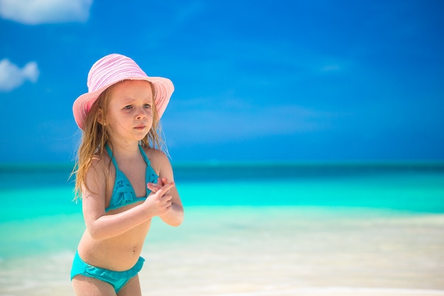 Adorable little girl in hat at beach during caribbean vacation