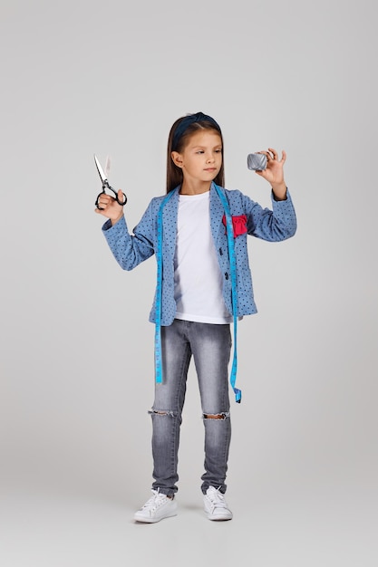 Adorable little girl holding tape measure and spool of thread