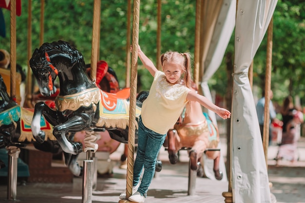 Adorable little girl near the carousel outdoors