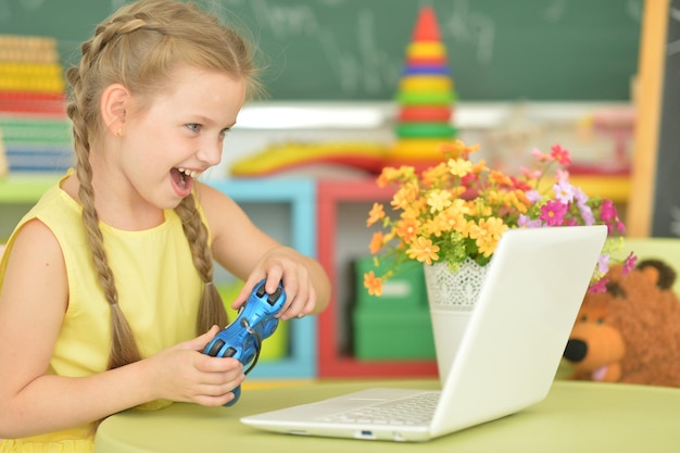 Adorable little girl playing computer game with laptop