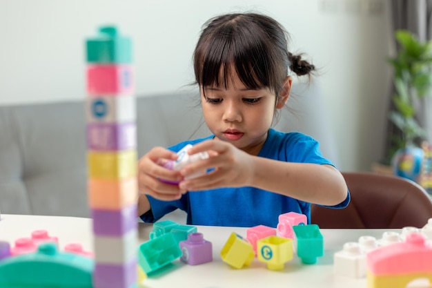 Adorable little girl playing toy blocks in a bright room