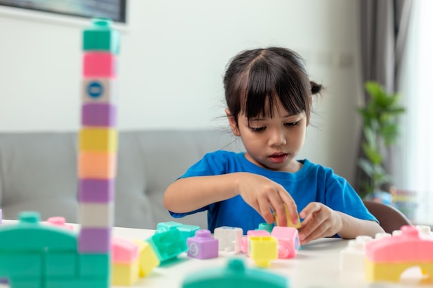 Adorable little girl playing toy blocks in a bright room