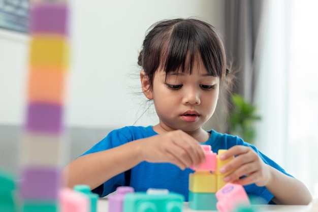 Adorable little girl playing toy blocks in a bright room