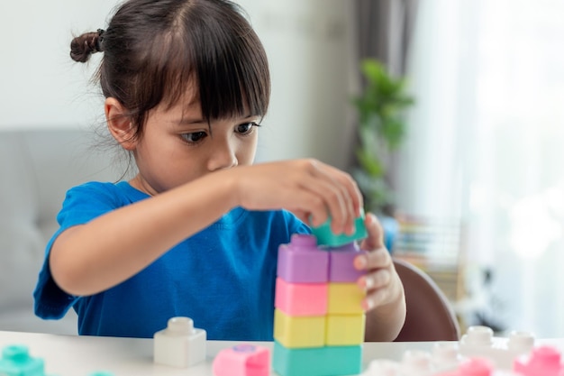 Adorable little girl playing toy blocks in a bright room