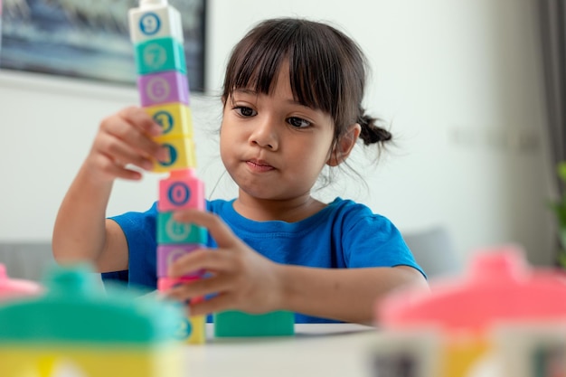 Adorable little girl playing toy blocks in a bright room