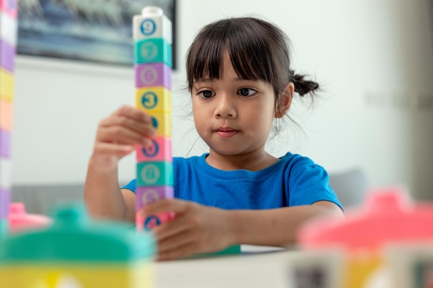 Adorable little girl playing toy blocks in a bright room