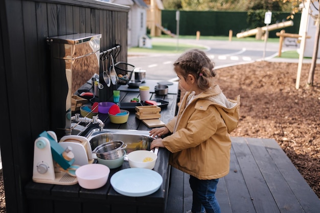 Adorable little girl playing in toy kitchen outdoors cute three year old girl have fun in kids city