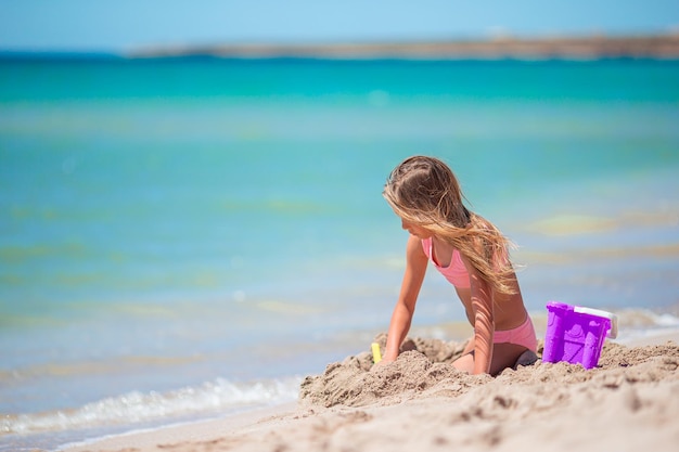 Adorable little girl playing with beach toys during tropical vacation