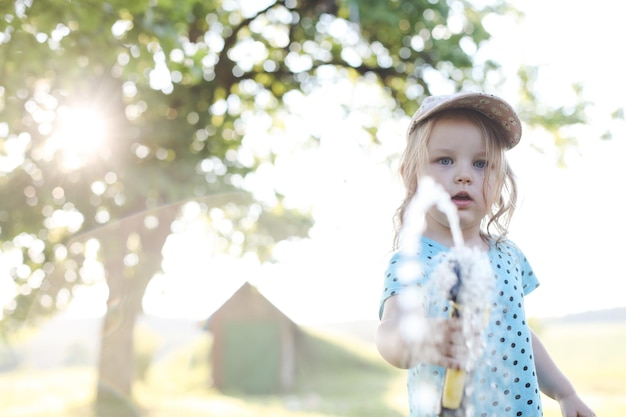 Adorable little girl playing with a garden hose on hot and sunny summer day