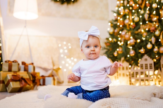 Adorable little girl playing with ornaments under decorated Christmas tree