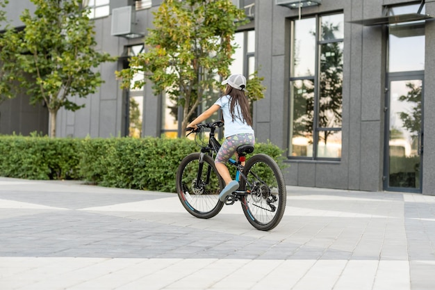 Adorable little girl riding a bike in a city