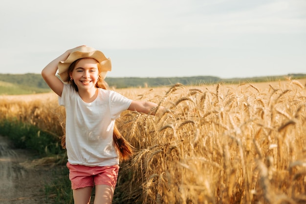 Adorable little girl runs happily on the road near the yellow wheat field child with a way of life a