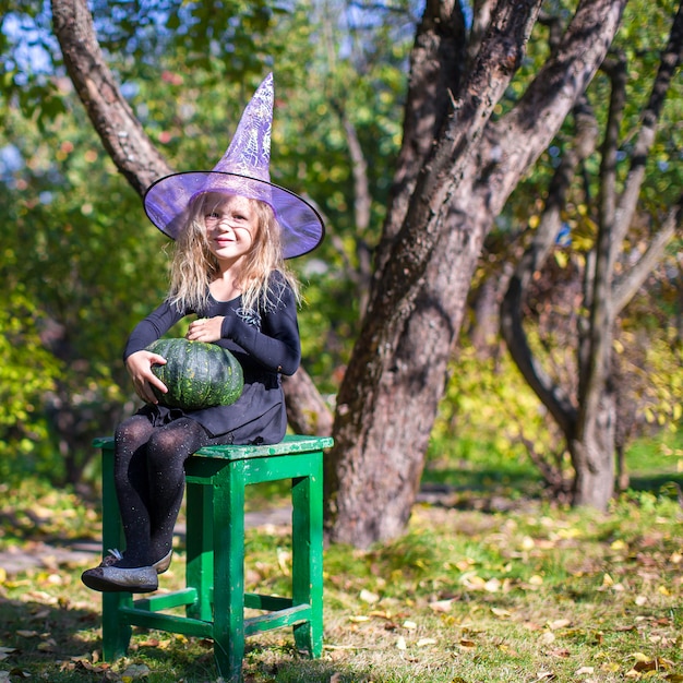 Photo adorable little girl in witch costume on halloween