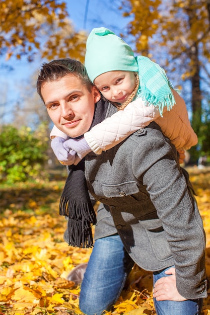 Adorable little girl with happy father having fun in autumn park on a sunny day