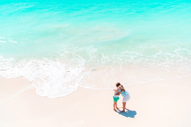 Adorable little girls have a lot of fun on the beach.