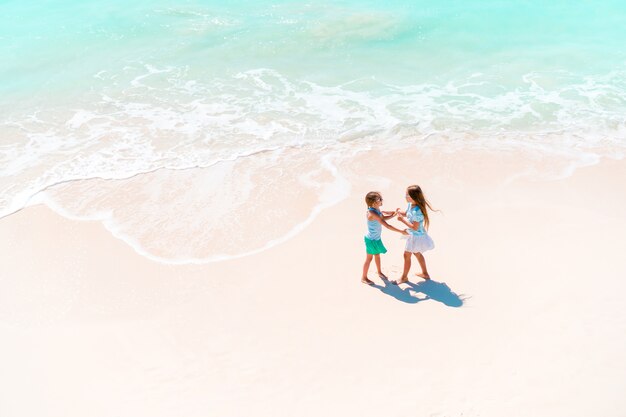 Adorable little girls have a lot of fun on the beach.