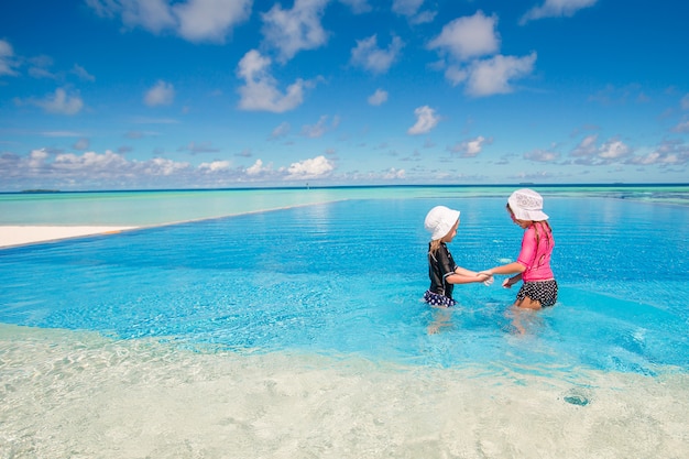 Photo adorable little girls playing in outdoor swimming pool on vacation