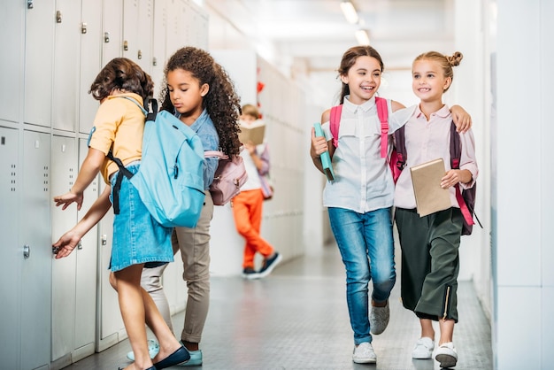 adorable little schoolgirls walking through school corridor