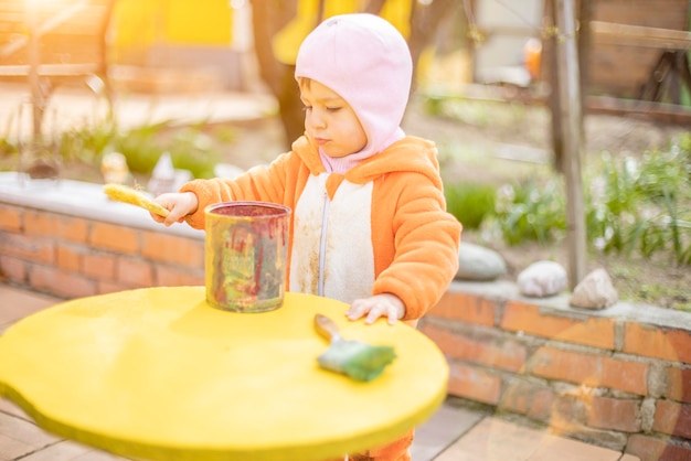 Adorable little toddler paints illuminated yellow round table with brush