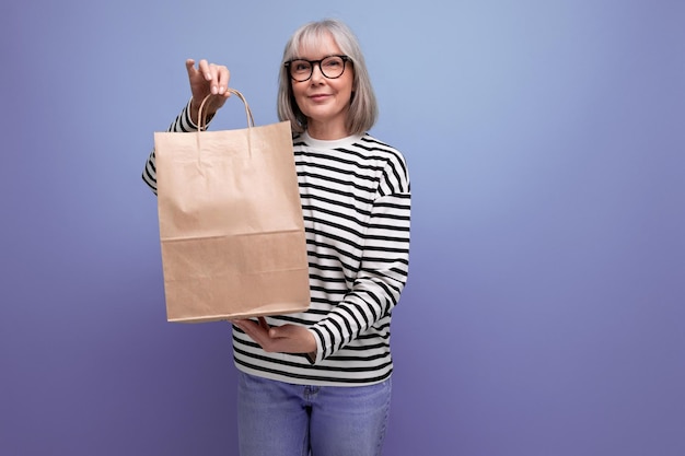 Adorable mature business woman with gray hair holding eco friendly shopping bag with mockup on