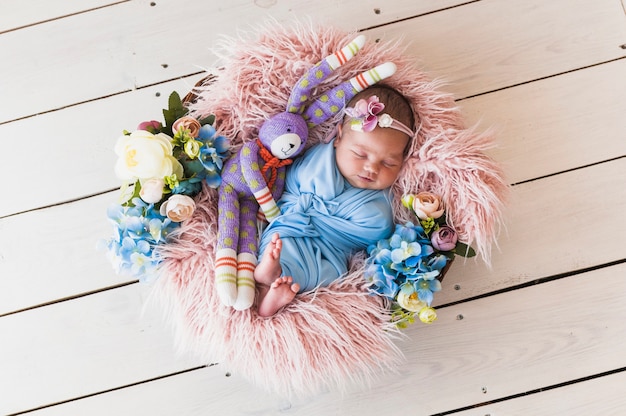 Adorable newborn with toy sleeping in basket