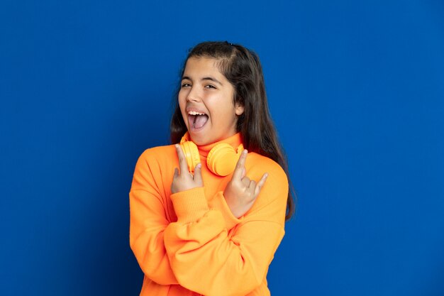 Adorable Preteen girl with yellow jersey gesturing over blue wall