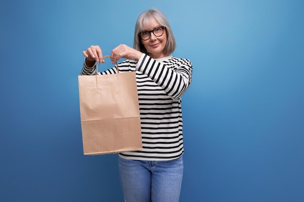 Adorable s mature business woman with gray hair holding eco friendly shopping bag mockup on bright