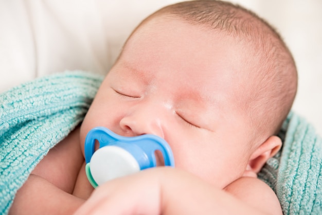 Adorable sleeping newborn baby with soother in the mouth