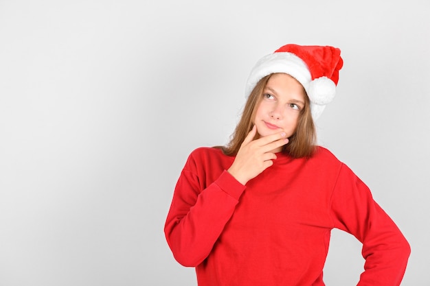 Adorable smiling girl with Santa red hat wearing red pullover 