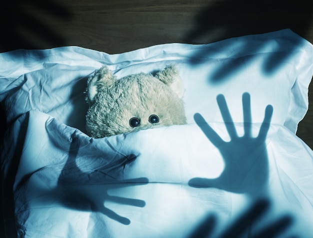 Adorable teddy bear laying in bed, scared