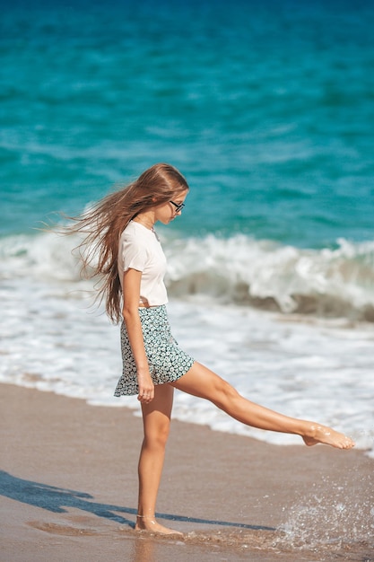 Adorable teen girl have fun at tropical beach during vacation at shallow water