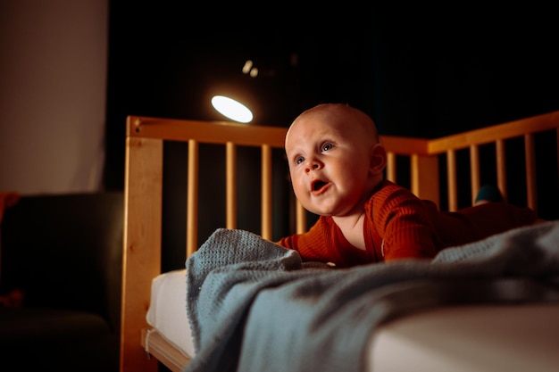 Adorable toddler baby boy with blue eye crawling on his stomach at night