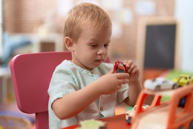 Adorable toddler playing with car toy sitting on table at kindergarten