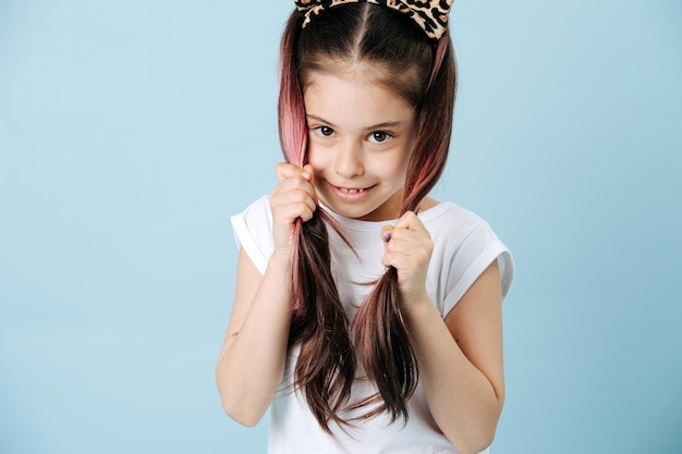 Adorable tween girl with cat ears holding hair tails in her hands