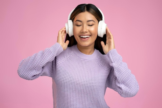 Adorable woman using wireless earphones for listening music