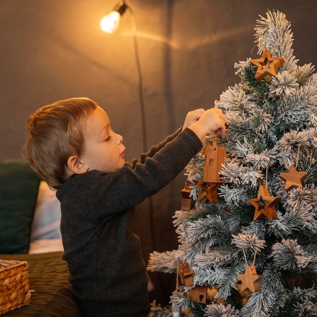 Adorable young boy decorating christmas tree