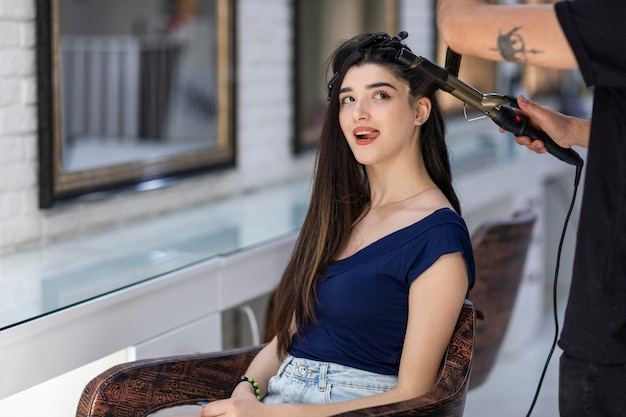 Adorable young girl sitting on the chair and take out her tongue at the barbershop High quality photo